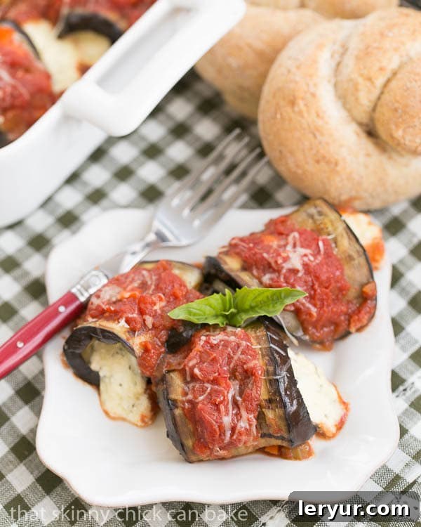 Creamy Ricotta and Mozzarella Stuffed Eggplant Rolls 5 Eggplant Rollatini with Ricotta and Mozzarella on a square white plate, elegantly garnished with fresh basil