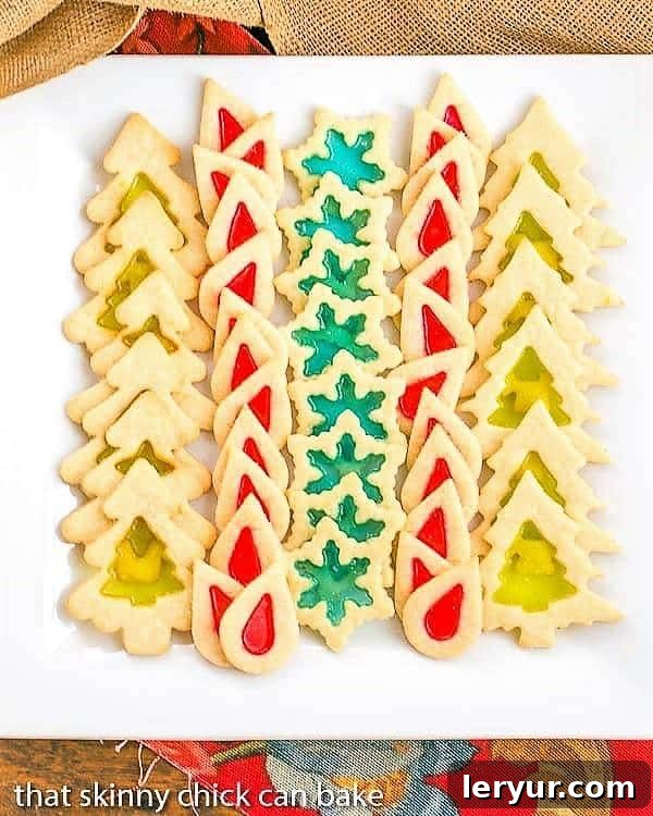 Stained Glass Cookies - Adding a little crushed candy to your sugar cookies makes for a fabulous holiday cookie! A delightful line-up of festive Stained Glass Cookies displayed on a pristine white square platter.