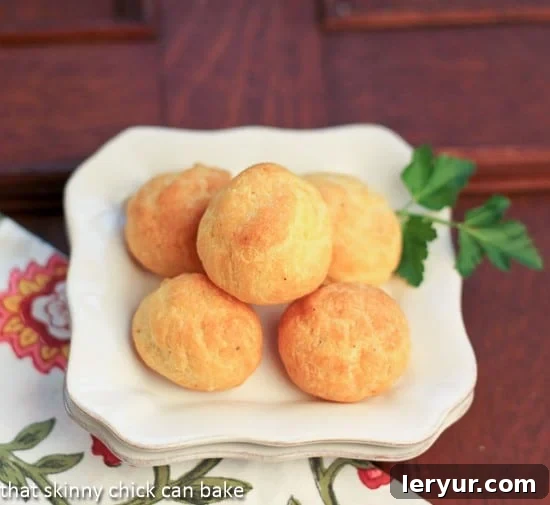 Beautifully golden French Cheese puffs on a white plate, ready to be enjoyed.