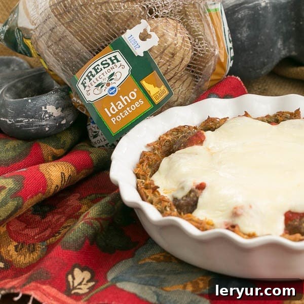 Italian Poutine Pie | A savory pie with a hash brown crust, marinara, meatballs and gooey mozzarella. A slice is cut, revealing the delicious layers.