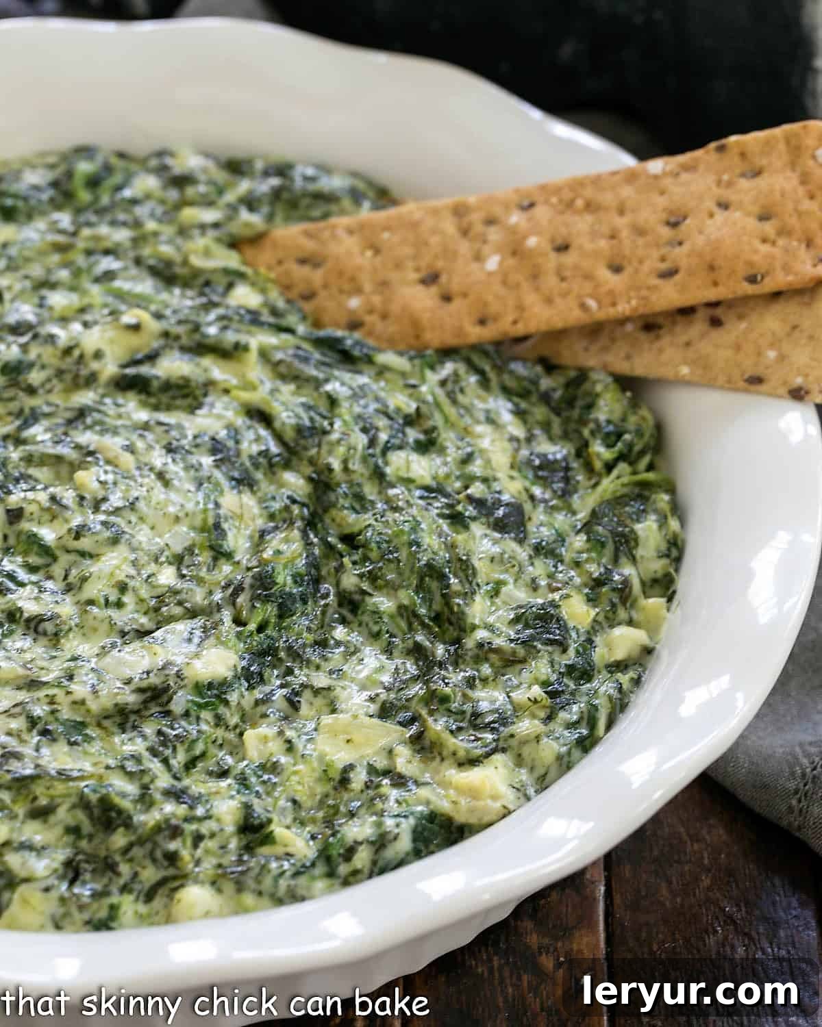 Experience the best Cheesy Spinach Dip recipe, a warm and creamy delight loaded with spinach, artichoke hearts, and multiple cheeses, perfect for any party or gathering. Baked Cheesy Spinach Dip in a white ceramic dish, ready to be served.