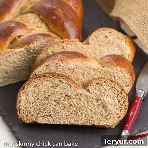 Indulge in the rich flavor and tender texture of our homemade Whole Wheat Challah, perfect for any occasion. Slices of golden-brown Whole Wheat Challah bread on a rustic slate tray, showcasing its tender texture.