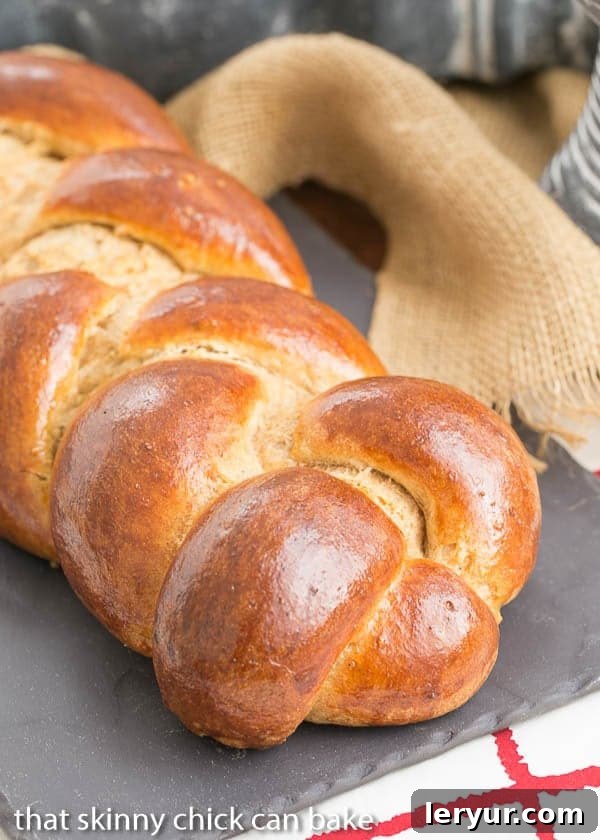 Experience the joy of baking your own Whole Wheat Challah with our easy-to-follow recipe. A freshly baked Whole Wheat Challah loaf, showcasing its intricate braid, resting on a slate tray.