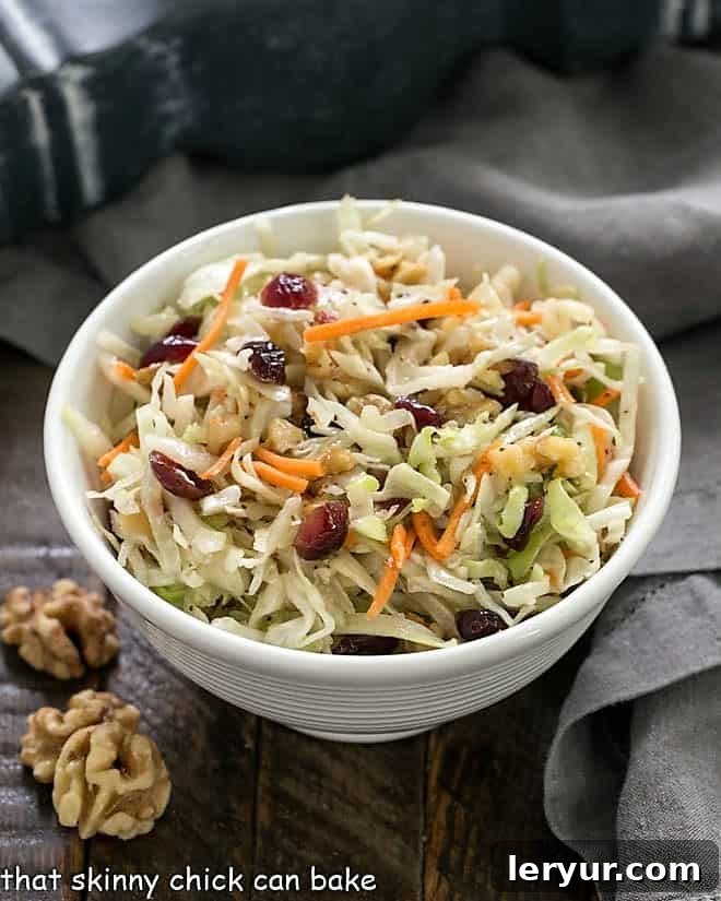 Easy coleslaw in a white bowl with walnuts to garnish