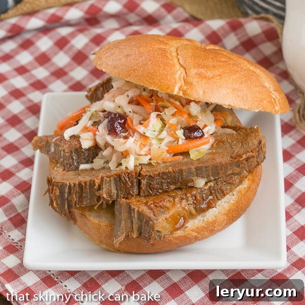 Texas brisket is typically a cut of beef that is smoked for a long time at a low temperature. When that's not possible, make this easy oven braised Texas brisket recipe for big, bold flavor in a juicy oven cooked beef brisket! Oven Braised Texas Brisket sandwich topped with coleslaw sits on a white plate with a red and white gingham tablecloth underneath