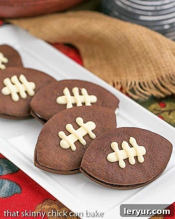 Chocolate Football Cookies - Chocolate cut-out cookies filled with buttercream and caramel! White platter with a number of Chocolate Football Cookies.