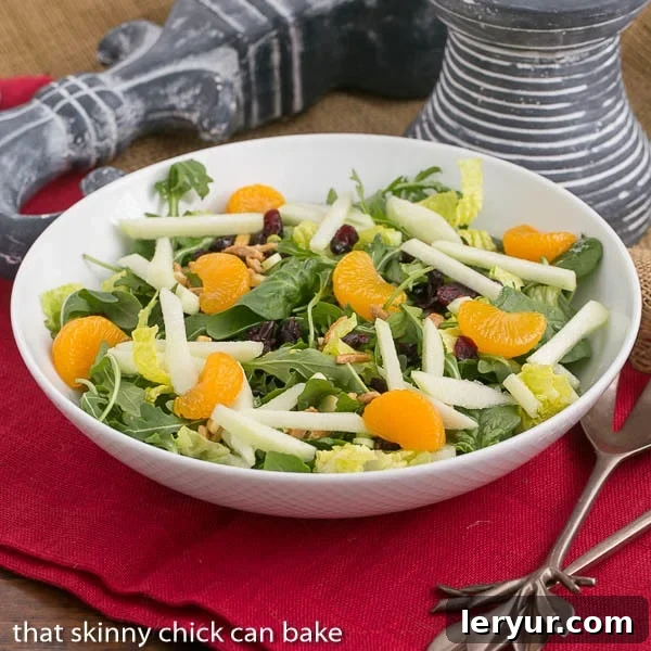 A stunning Holiday Lettuce Salad in a elegant white serving bowl, garnished with fresh cranberries.