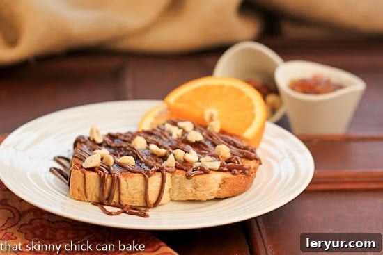 A close-up view of a Nutella Tartine garnished with a generous sprinkle of toasted chopped hazelnuts on a pristine white plate, highlighting the rich textures and inviting flavors.