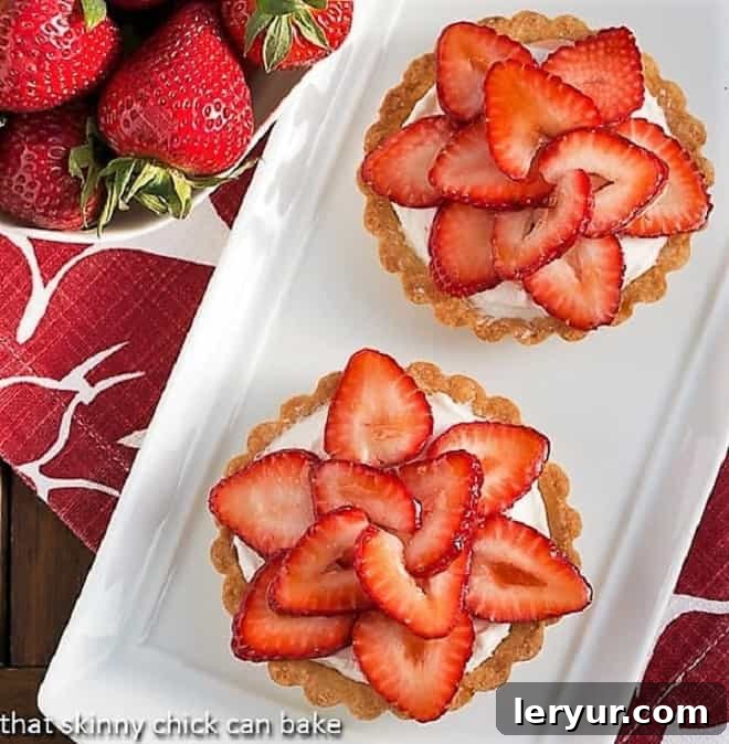 Delicious mini desserts with buttery tart shells, cream cheese filling, and a beautiful topping of sweet, ripe strawberries, perfect for a spring gathering.