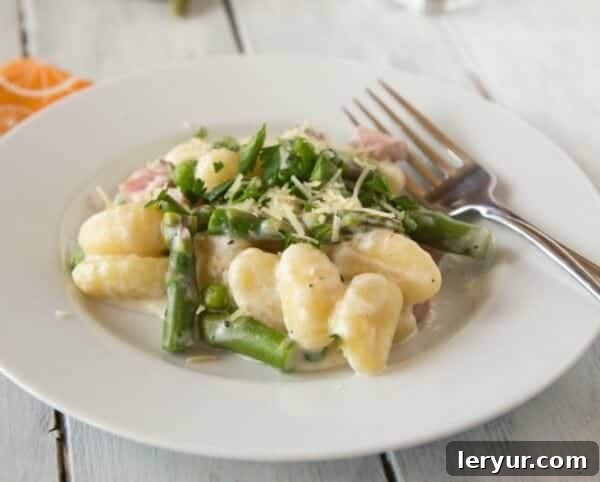 Pillowy gnocchi served in a rich, flavorful cream sauce, generously topped with savory ham and tender, crisp asparagus, perfect for a spring main course.