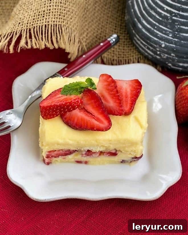 Berry Tiramisu with Grand Marnier - A strawberry twist on the Italian classic with mascarpone and Grand Marnier soaked ladyfingers! Close-up of Berry Tiramisu with Grand Marnier garnished with fresh strawberry slices and mint, served on a square white plate.