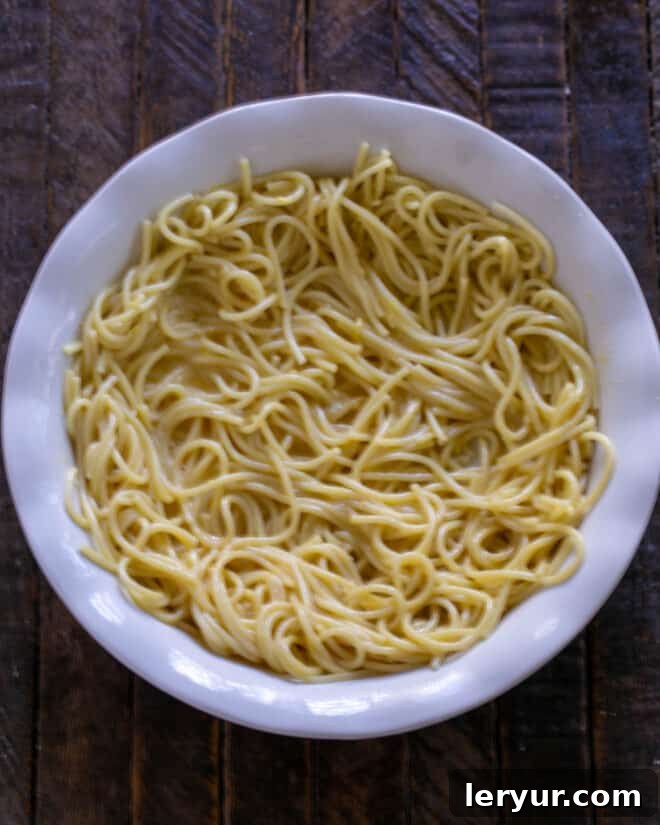 The spaghetti, egg, and Parmesan mixture carefully pressed into a pie plate, forming the crust.