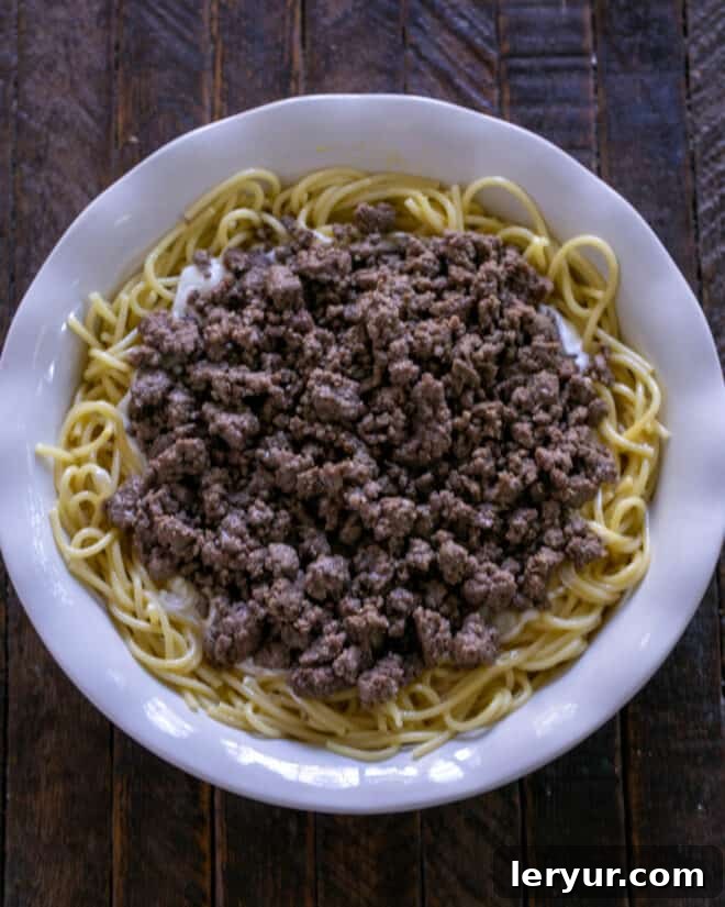 A generous layer of seasoned ground beef spread over the sour cream layer in the spaghetti pie.