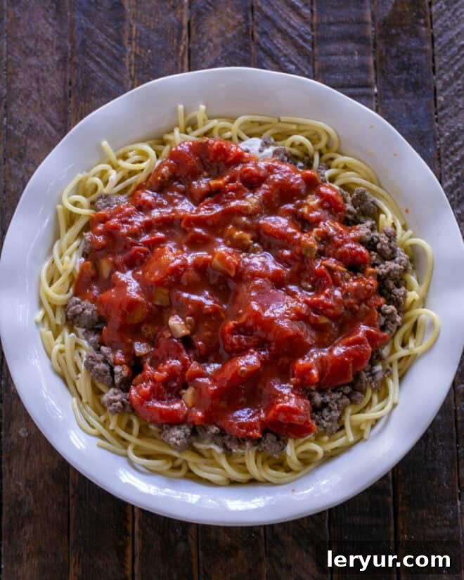 Rich marinara sauce evenly spread over the ground beef layer of the spaghetti pie.