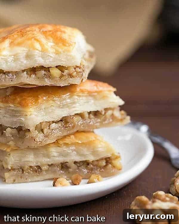 Greek Baklava Recipe - My mom's baklava with layers of buttery filo & a walnut filling doused with orange blossom water kissed sugar syrup Diamonds of Baklava Recipe stacked on a small white plate.