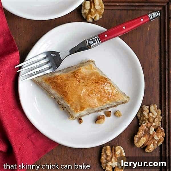 Greek Baklava Dessert - My mom's baklava with layers of buttery filo & a walnut filling doused with orange blossom water kissed sugar syrup Overhead view of a slice of Classic Greek Baklava slice on a white plate.