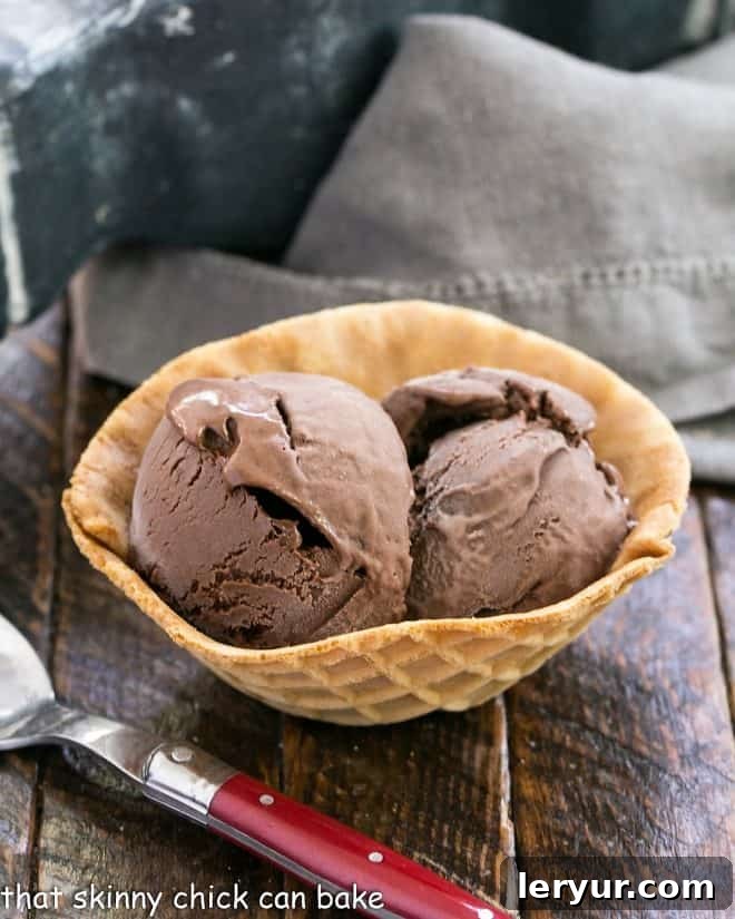 Decadent Chocolate Velvet Ice Cream 2 Chocolate Velvet ice cream in a waffle bowl with a red handled spoon, showcasing its rich, dark color and creamy texture.