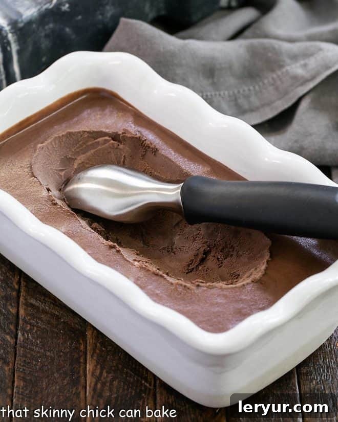 Decadent Chocolate Velvet Ice Cream 3 Chocolate Velvet Ice cream in a white ceramic terrine with an ice cream scoop, ready to be served.