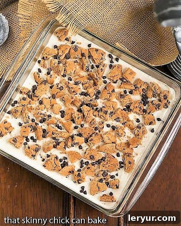 Overhead view of a finished Milk & Cookies Lasagna in a square glass baking dish, showing off its layers.