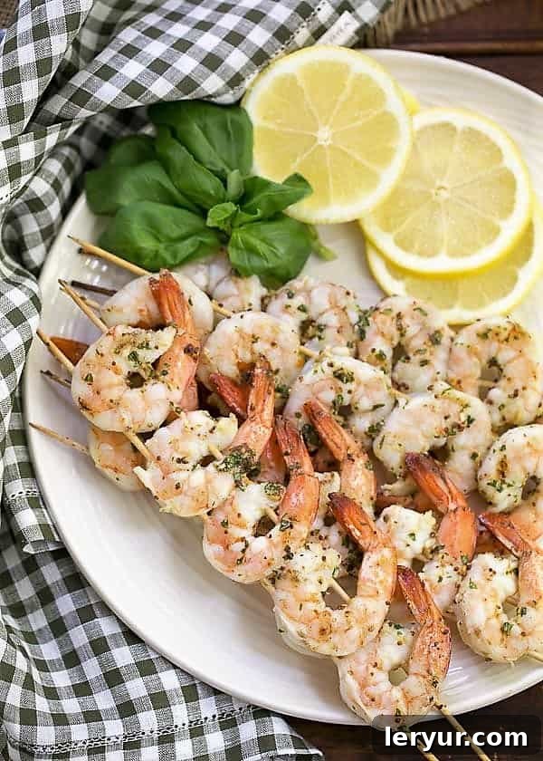 Perfectly grilled shrimp scampi skewers, garnished with fresh basil and lemon slices, ready to be served.