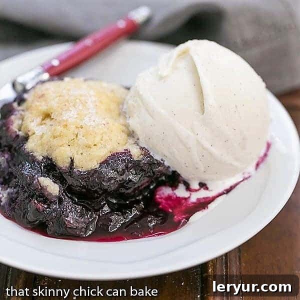 Grilled Blueberry Cobbler - A rustic berry dessert made on the BBQ! Grilled Blueberry Cobbler on a white dessert plate topped with a scoop of ice cream.