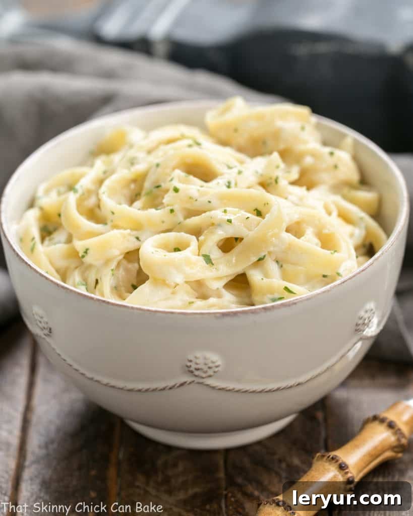 Light Fettuccine Alfredo - A creamy flavorful, lightened up Fettuccine Alfredo that tastes amazing! Light Fettuccine Alfredo in a white bowl garnished with parsley.