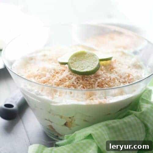 Layers of Coconut Key Lime Trifle in a large glass bowl, showing coconut flakes and lime filling.