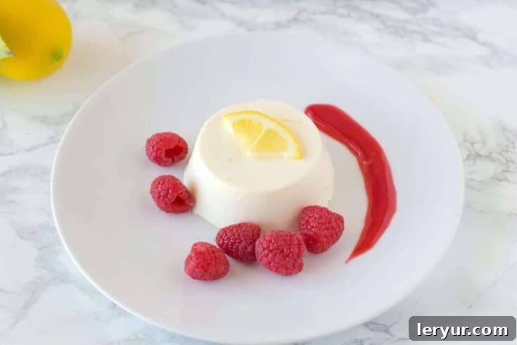 Elegant Lemon Panna Cotta with Raspberry Sauce, garnished with fresh berries and mint.