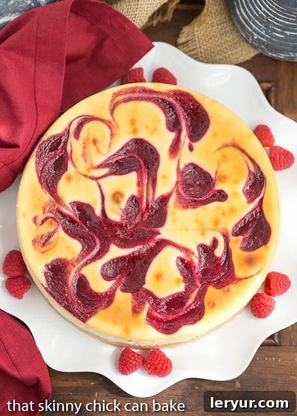 Overhead view of a stunning White Chocolate Raspberry Swirl Cheesecake presented on a pristine white serving plate, elegantly adorned with an arrangement of fresh, ripe raspberries, highlighting its vibrant colors and sophisticated design.