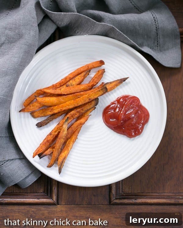 Overhead view of Spicy Sweet Potato Fries on a white plate with ketchup.