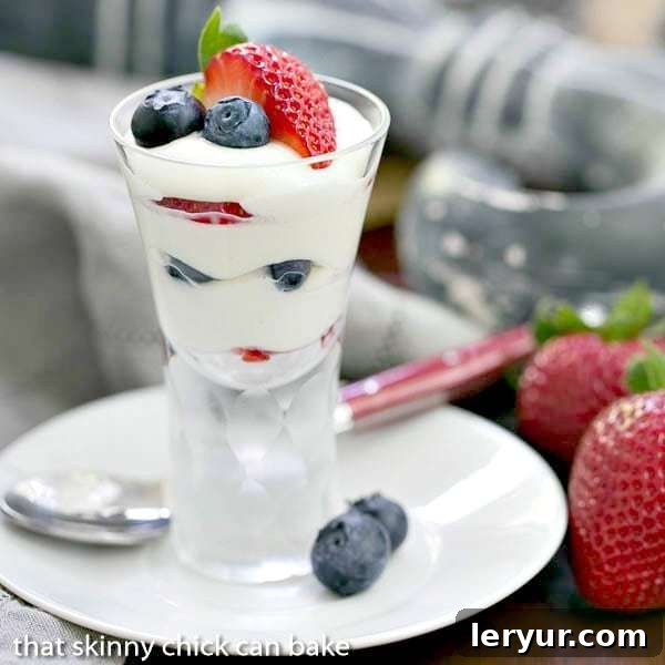 White Chocolate Berry Parfaits - Luscious ripe berries layered with a Frangelico spiked white chocolate mousse Individual White Chocolate Berry Parfaits garnished with fresh blueberries and strawberries, ready to serve, arranged on a small plate.