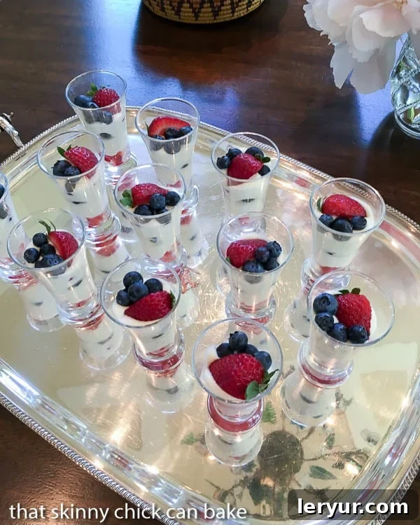 White Chocolate Berry Parfaits - Luscious ripe berries layered with a Frangelico spiked white chocolate mousse A silver tray filled with individual White Chocolate Berry Parfaits, garnished with fresh berries and ready for guests to enjoy at a gathering.