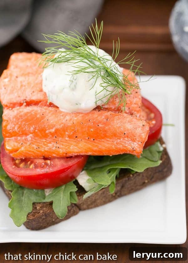 Open-Faced Salmon Sandwiches with Herb Cucumber Relish on a square white plate with a dollop of relish and dill sprig to garnish, highlighting the freshness and gourmet presentation.