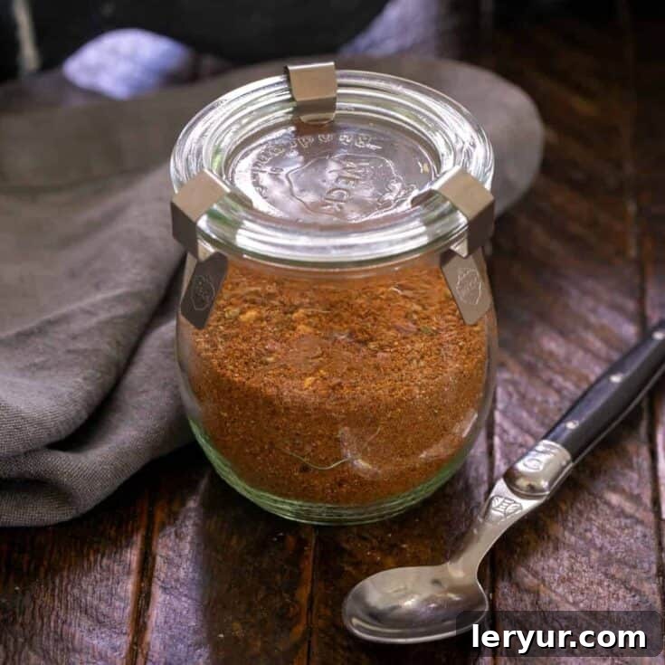 Square image of Taco seasoning in a glass container with a black handled spoon.