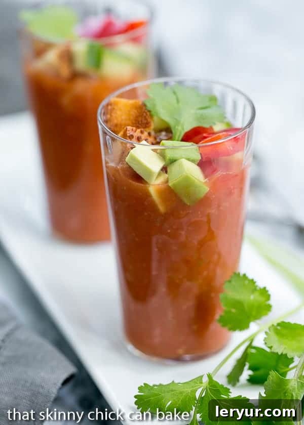 Chilled Gazpacho Sips 2 An array of vibrantly garnished Gazpacho Shooters displayed on a clean white tray, highlighting fresh vegetable toppings and herbs.