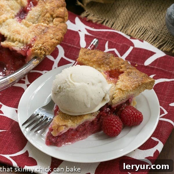 Berry Bliss: 50+ Irresistible Dessert Ideas 11 A classic Lattice-Topped Raspberry Pie, served on a white plate with a scoop of vanilla ice cream and a fork.