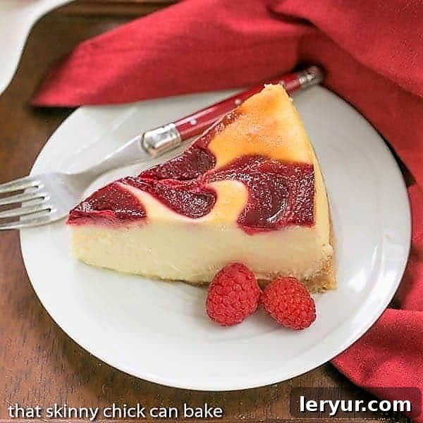 Savor our White Chocolate Raspberry Swirl Cheesecake - a luscious, creamy white chocolate cheesecake topped with a beautifully marbleized raspberry swirl, creating a stunning and delicious dessert. A perfectly sliced White Chocolate Raspberry Swirl Cheesecake on a white plate, adorned with fresh raspberries and a red-handled fork.