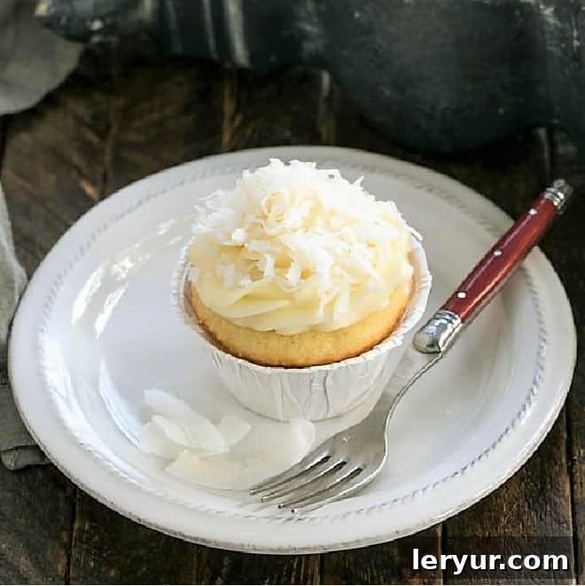 Coconut Cupcakes, fluffy and moist, topped with a generous swirl of cream cheese icing and toasted coconut flakes.