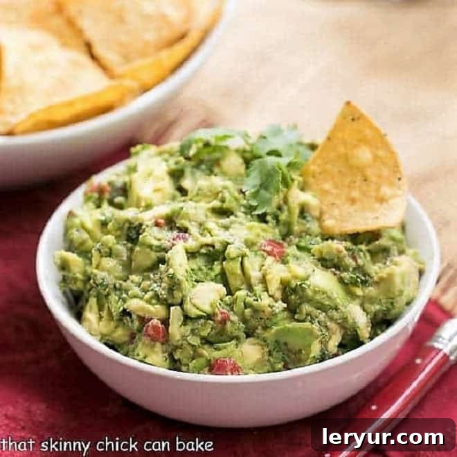 Fresh Guacamole, chunky and green, topped with diced tomatoes and cilantro, ready for scooping.