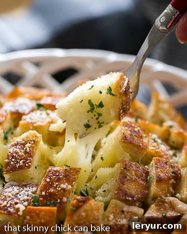 Cheesy Garlic Bread - A crosshatch cut loaf full of melty cheese and garlic! Cheesy Garlic Bread with a fork full of gooey bread on a fork.