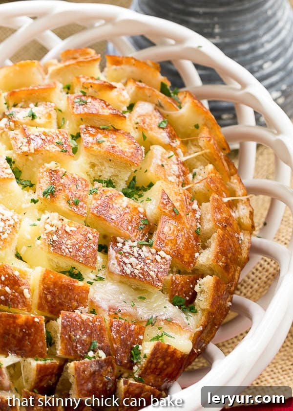 Cheesy Garlic Bread - A crosshatch cut loaf full of melty cheese and garlic! Close up view of Cheesy Garlic Bread in a white ceramic basket.