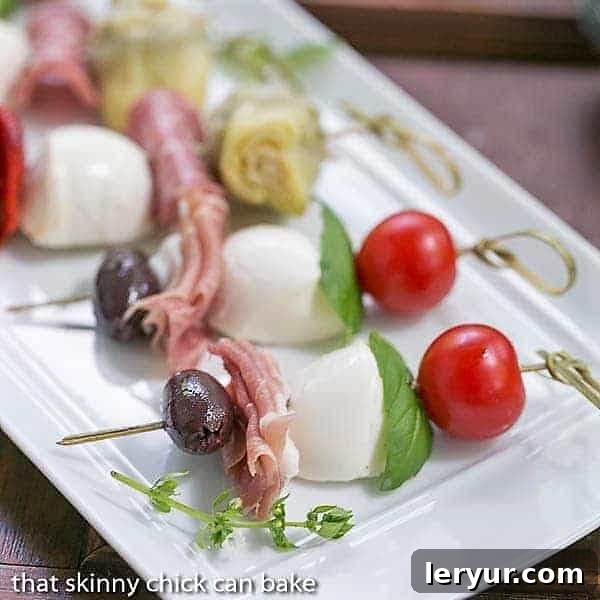 Close up shot of various ingredients on Antipasto Skewers on a white tray, showcasing texture and color.