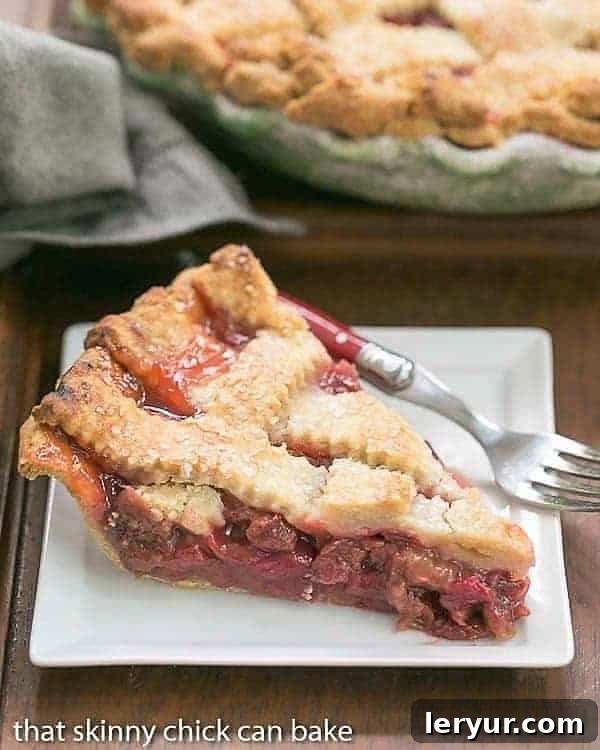 A perfectly baked slice of Classic Rhubarb Pie, featuring a golden lattice crust, served on a pristine white square dessert plate.