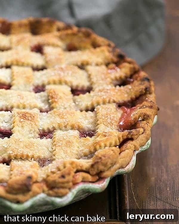 A whole Classic Rhubarb Pie, adorned with a delicate lattice crust, cooling gracefully in a ceramic pie plate.