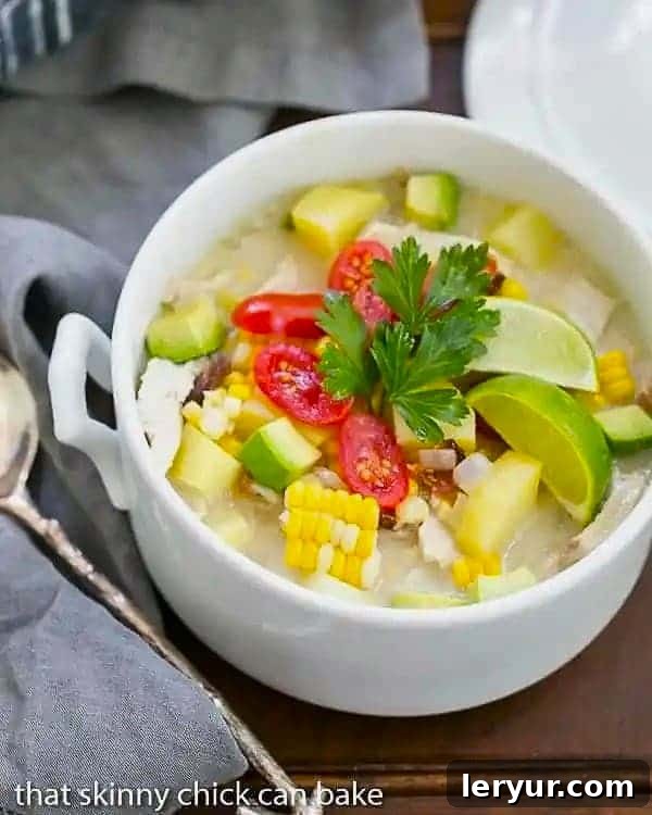 A beautiful white soup tureen filled with creamy Chicken Corn Chowder, garnished and ready to be served.