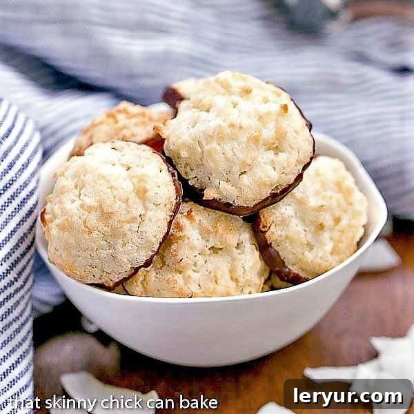 Decadent Chocolate Coconut Macaroons 2 Delicate Chocolate Dipped Coconut Macaroons resting in a white bowl, showcasing their golden-brown edges and luscious chocolate bases.