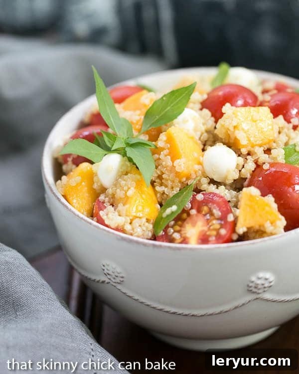Vibrant Peach Quinoa Caprese Salad in a white bowl, garnished with fresh basil leaves, ready to be served