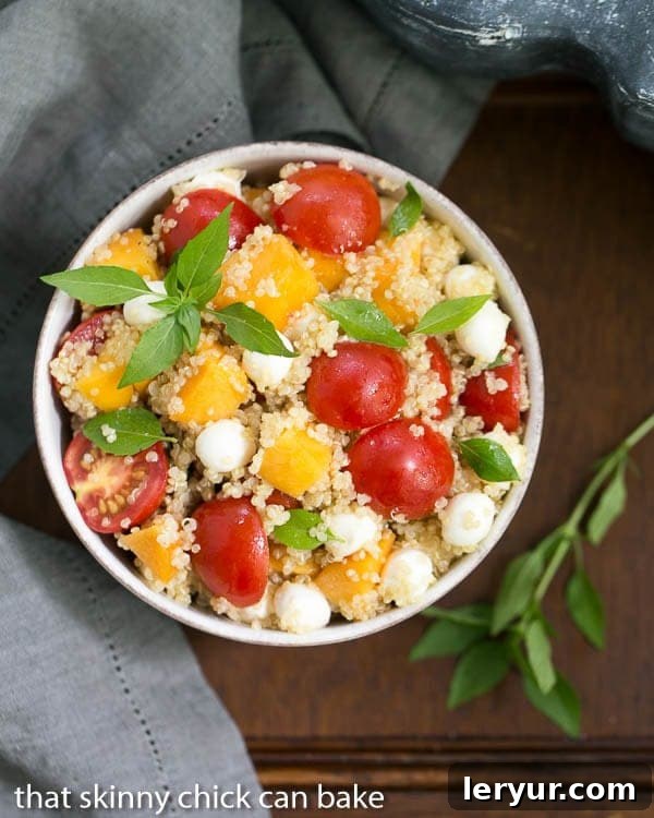 Overhead view of Peach Quinoa Caprese Salad in a white bowl, beautifully garnished with fresh basil leaves, showcasing its colorful ingredients
