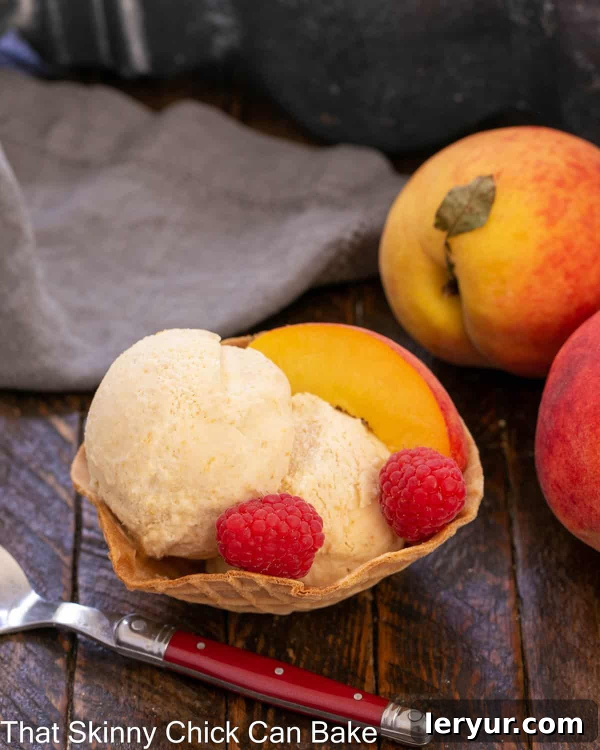 No Churn Roasted Peach Ice Cream - Savor the summer with this easy, homemade peach ice cream No-churn peach ice cream in a sugar cone bowl with raspberry and peach garnishes.