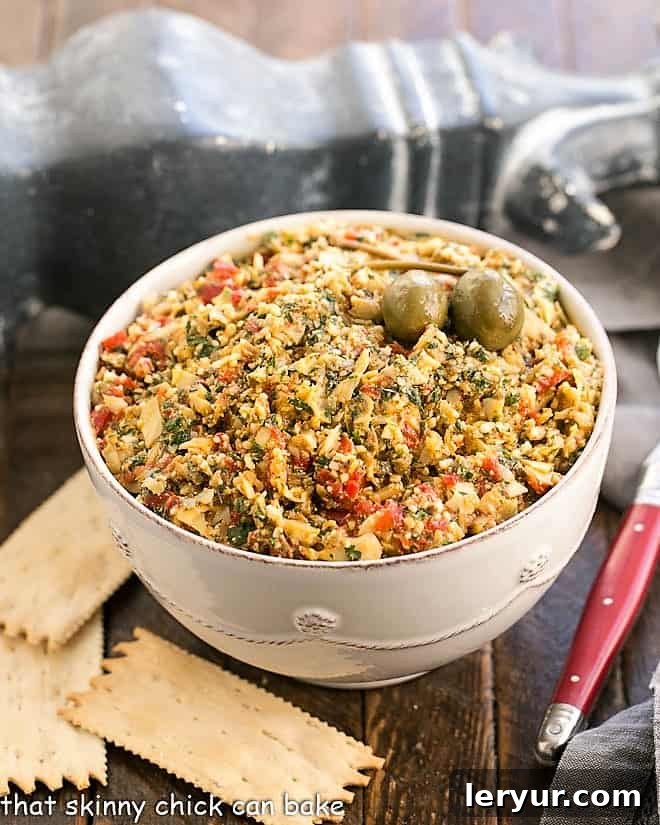 Roasted Red Pepper Artichoke Tapenade in a white serving bowl, garnished with fresh parsley.